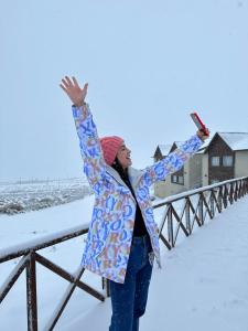 uma mulher parada na neve com os braços no ar em Edenia Hotel & Nature em El Calafate