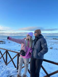 a man and woman standing next to a fence in the snow at Edenia Hotel & Nature in El Calafate