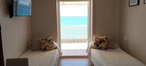 two beds in a room with a view of the ocean at Apartamentos Don Pepe in Torremolinos