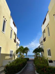 un camino entre dos edificios con el océano en el fondo en Habitación privada en Dixon Cove Roatan, en Roatan