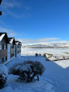 a snow covered yard with a house and a boat at Edenia Hotel & Nature in El Calafate