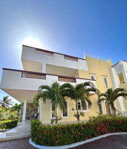 een geel gebouw met palmbomen ervoor bij Habitación privada en Dixon Cove Roatan in Roatan