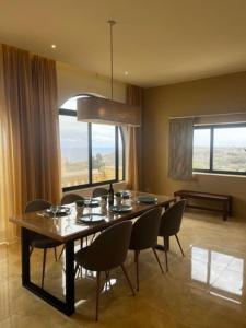 a dining room with a table and chairs and windows at Spacious, Bright, Valley & Sea View Maisonette in Xagħra