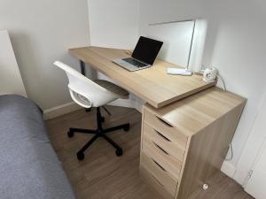 escritorio de madera con ordenador portátil y silla en Les Jardins Des Chambrettes, en Clermont-Ferrand