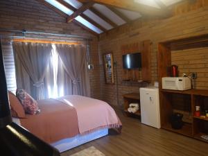 1 dormitorio con 1 cama y microondas en una habitación en Chalés Corucacas en Cambará