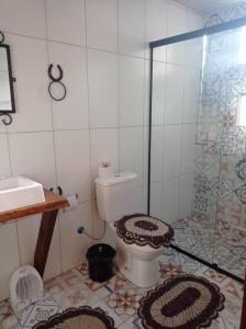 uma casa de banho com um WC e uma cabina de duche em vidro. em Chalés Corucacas em Cambará