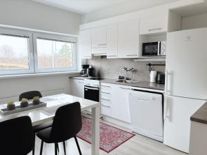 eine Küche mit weißen Geräten sowie einem Tisch und Stühlen in der Unterkunft Hamina City Apartments in Hamina