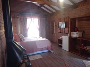 Schlafzimmer mit einem Bett und einem Fenster in der Unterkunft Chalés Corucacas in Cambará