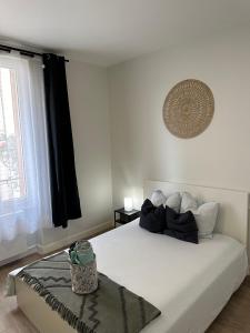 Dormitorio blanco con cama con almohadas blancas en Les Jardins Des Chambrettes en Clermont-Ferrand