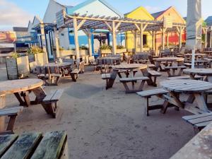 un grupo de mesas de picnic y bancos en la playa en Coastal Bungalow, en Prestatyn