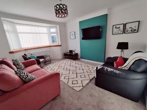 a living room with two couches and a flat screen tv at Coastal Bungalow in Prestatyn