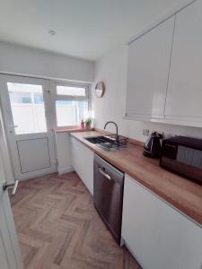 a kitchen with white cabinets and a wooden counter top at Coastal Bungalow in Prestatyn
