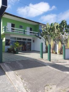 un edificio verde y blanco con palmeras delante en Flats Divina Ilha, en Ilha Comprida