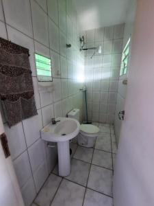 Baño blanco con aseo y lavamanos en Flats Divina Ilha, en Ilha Comprida