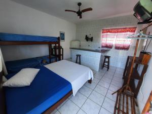 1 dormitorio con 1 cama azul y cocina en Flats Divina Ilha, en Ilha Comprida
