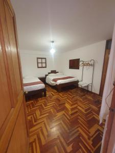 a room with two beds and a wooden floor at shanti pisac in Pisac