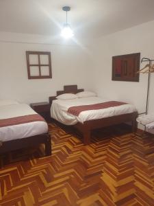 um quarto com 2 camas e piso em madeira em shanti pisac em Písac