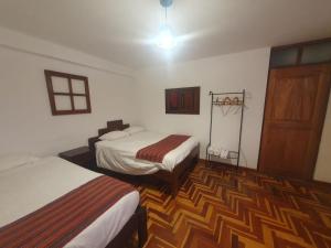 a room with two beds and a wooden floor at shanti pisac in Pisac