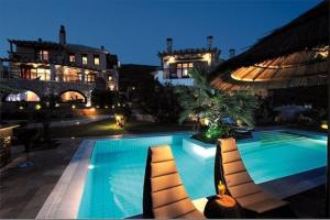 a swimming pool with lounge chairs next to a building at Iakovakis Suites & Spa in Koropi
