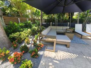 a patio with a bench and an umbrella and some flowers at 6 Bedroom 6 Bath Guesthouse on Duval Street in Key West