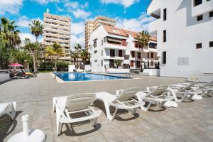 patio z krzesłami, basenem i budynkami w obiekcie Family Duplex Altamira Playa Las Americas Tenerife South w Aronie