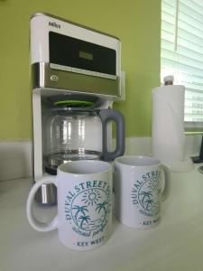 a kitchen counter with two cups and a coffee maker at Duval Street Suite w kitchen and shared heated pool in Key West