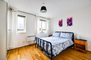 a bedroom with a bed and two windows at River views from Canary Wharf in London