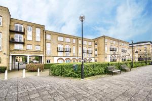 Un gran edificio de ladrillo con bancos delante. en River views from Canary Wharf, en Londres