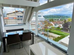 einen Balkon mit einem Tisch und Stühlen sowie großen Fenstern in der Unterkunft Cozy Escape House 12 min away from Zurich Main Station in Ober Urdorf