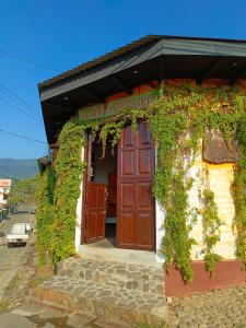 a building covered in ivy with a red door at Hotel Anáhuac in Juayúa