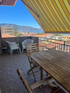 eine Terrasse mit einem Holztisch und Stühlen auf dem Balkon in der Unterkunft Casa vacanza Alcamo Marina in Alcamo