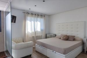 una camera da letto bianca con un letto e una finestra di The Beach-house a Massalfassar Altre 16 foto