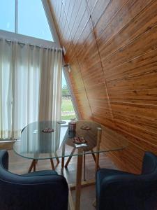 uma sala de jantar com uma mesa de vidro e parede de madeira em Vallecito Lodge em Muyurina