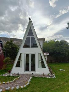 een driehoekig huis met ramen in een tuin bij Vallecito Lodge in Muyurina