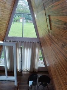 an attic room with a large window and a chair at Vallecito Lodge in Muyurina