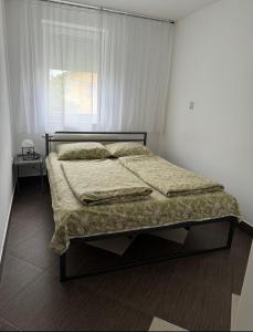 a bed in a white bedroom with a window at Bellas apartmani in Novi Sad