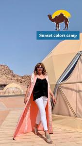 Una donna è in piedi accanto a una tenda di Sunset colors camp a Wadi Rum
