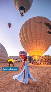 a woman in a dress walking in front of hot air balloons at Sunset colors camp in Wadi Rum