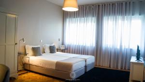 une chambre avec un lit et une grande fenêtre dans l'établissement Espinho Vintage - Alojamento de Charme, à Espinho
