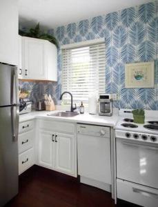 a kitchen with white cabinets and a blue and white wallpaper at Two Duval Street Suites w pool in Key West