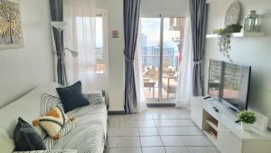 een woonkamer met een bank en een groot raam bij Benalmadena Minerva - Ocean view 1 Bedroom apartment in Benalmádena