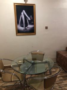 una mesa de cristal con 2 sillas y una foto en la pared en Dazzle Hotels and Apartments en Jidu