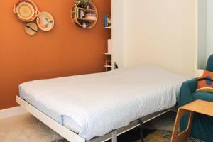 een bed in een kamer met een oranje muur bij Studio with terrace near Paris in Boulogne-Billancourt