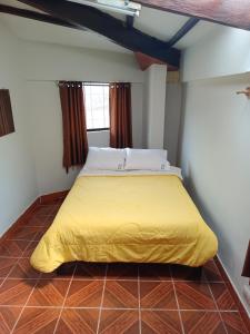 Bett in einem Zimmer mit gelber Tagesdecke in der Unterkunft Oro Verde Hostal in Cusco
