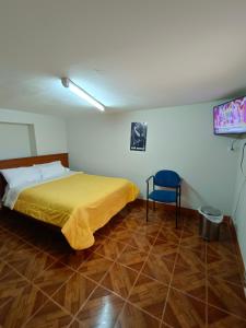 ein Schlafzimmer mit einem Bett und einem blauen Stuhl in der Unterkunft Oro Verde Hostal in Cusco
