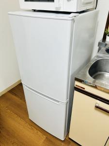 a white refrigerator with a microwave on top of it at GUEST HOUSE GREEN BASE HAKATA in Fukuoka