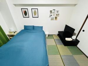 1 dormitorio con 1 cama azul y 1 silla en GUEST HOUSE GREEN BASE HAKATA en Fukuoka