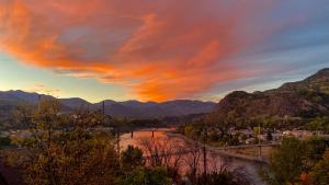 a sunset over a river with a bridge and mountains at Comfy Home in Trail