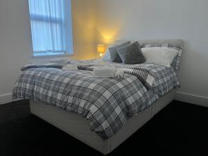 a bedroom with a large bed with a plaid blanket at Ashfield New Place in Newcastle under Lyme