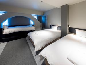 1 dormitorio con 2 camas y un arco en el centro en New Osaka Hotel, en Osaka